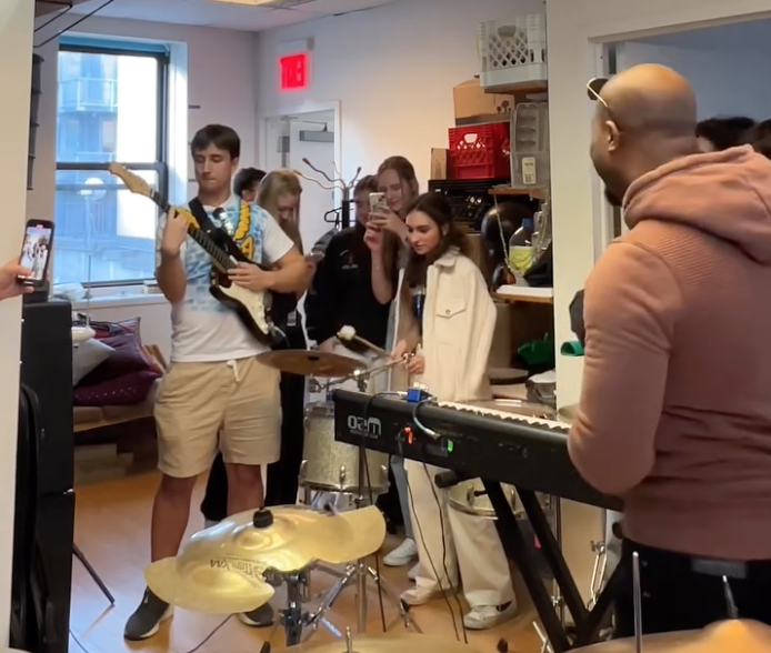 Eli Johnson in a studio session surrounded by young musicians with instruments at Fresh Produce Studio